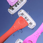 Four colourful "billie" razor heads intersect on a blue background, glistening with water droplets.