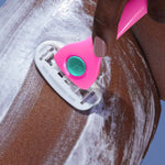 Pink "Billie" razor shaves foam-covered skin, held by hand against smooth surface with blue background.