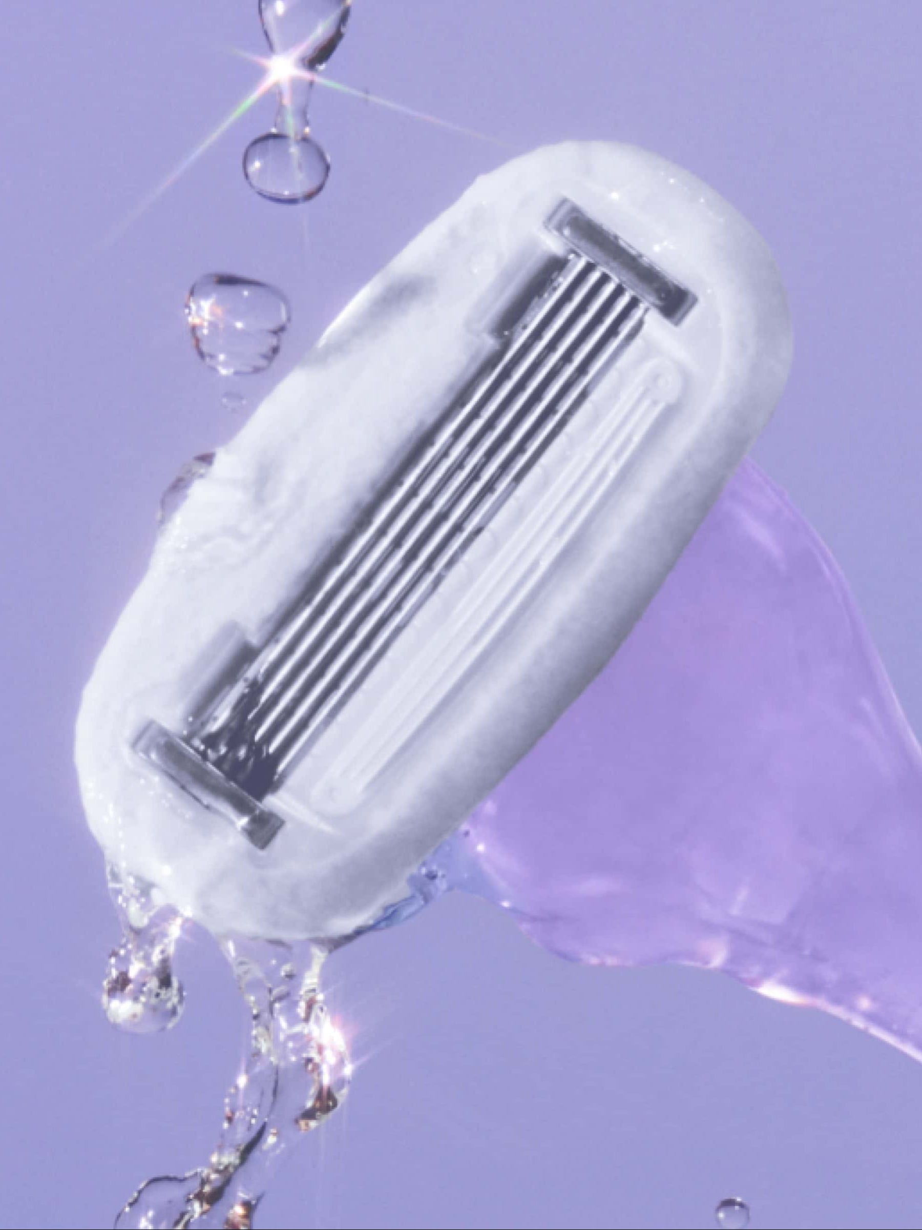 A razor head with multiple blades, water droplets glistening around it, set against a soft purple background.