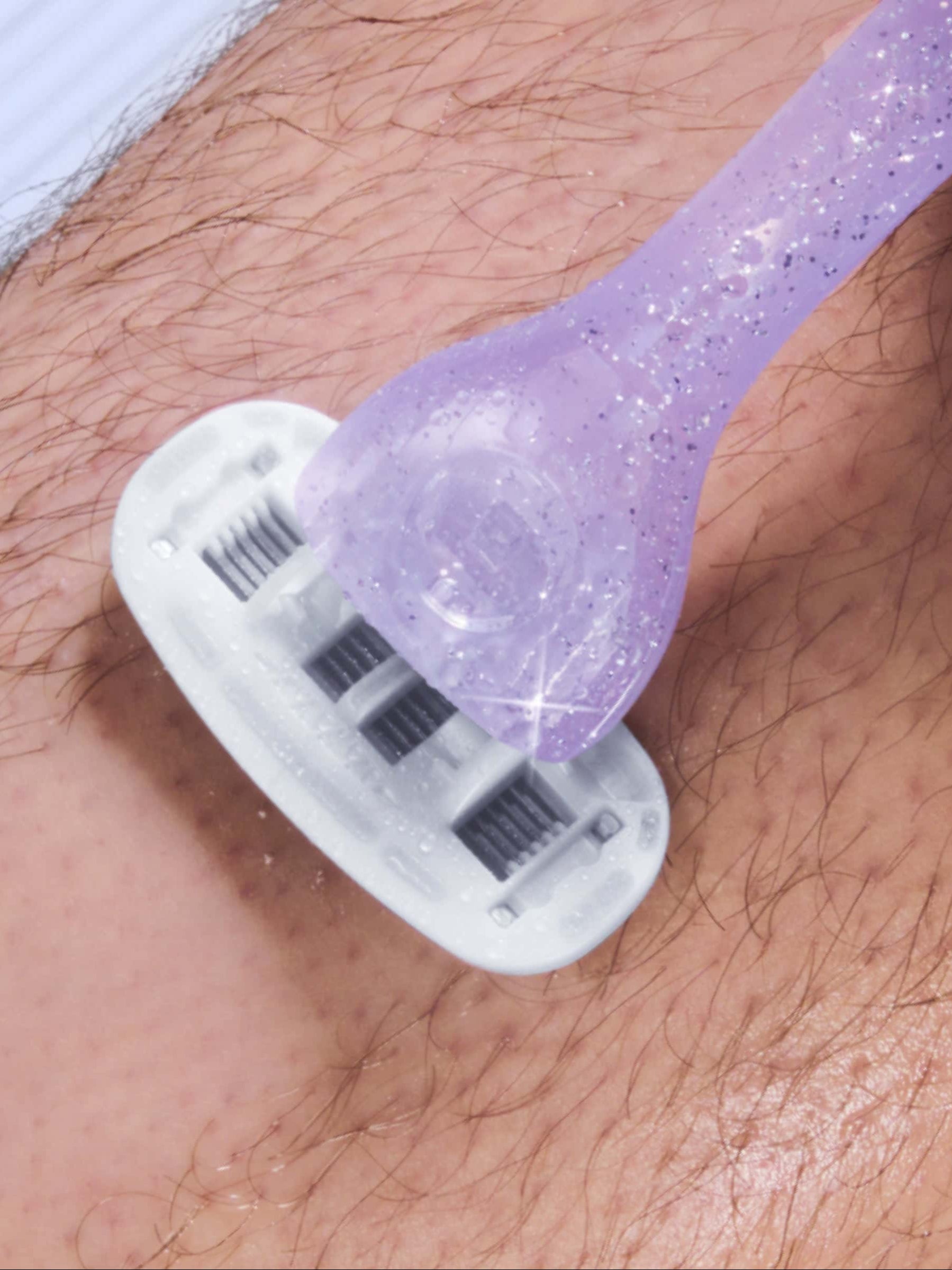 A purple shaver glides over a hairy surface, removing hair and leaving a smooth path, in a close-up view of shaving.