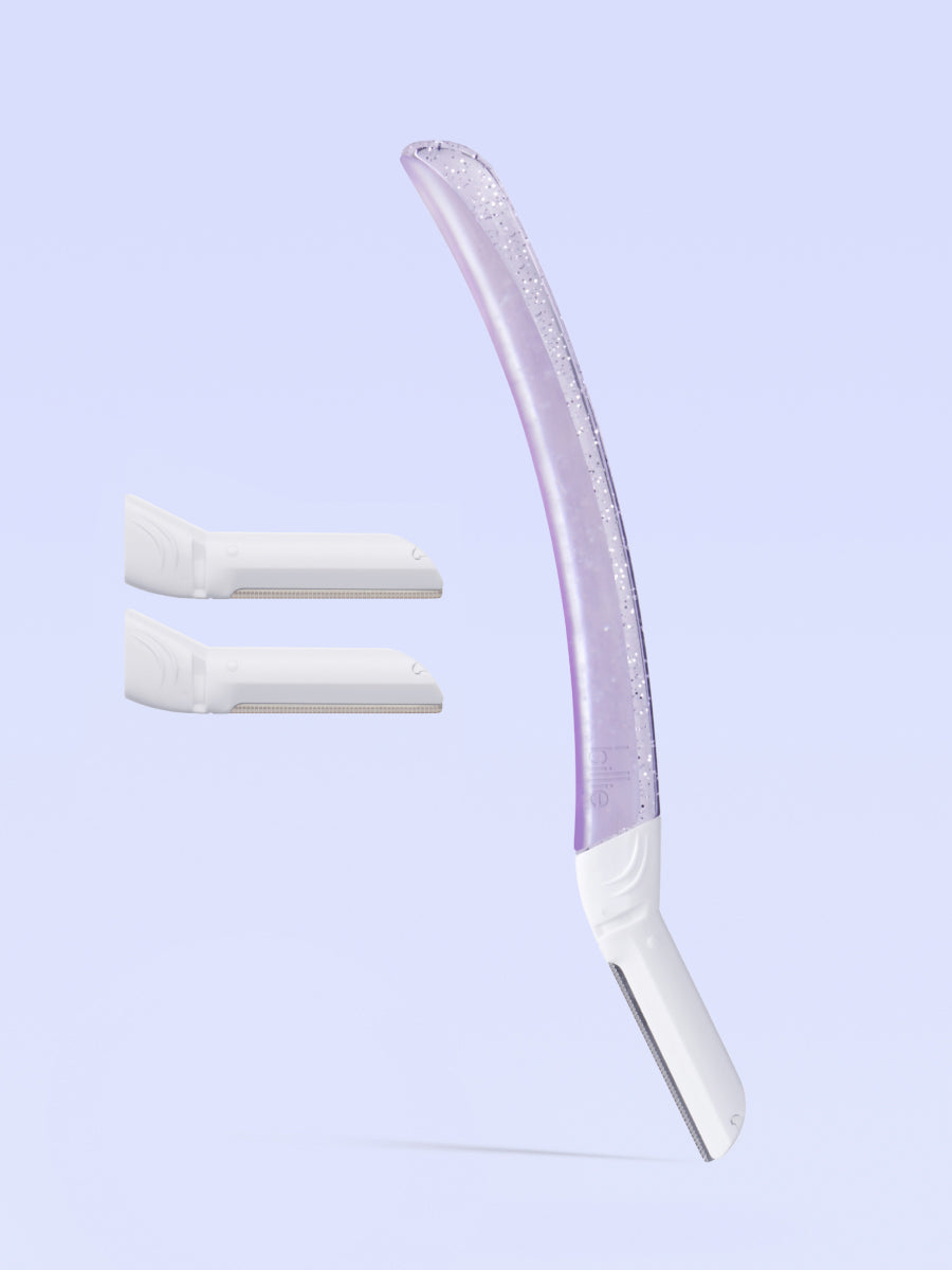 Curved purple Billie razor with translucent handle and two white blade refills on soft blue background.