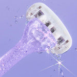 Glittery purple razor with water droplets mid-air, highlighting its textured handle and multi-blade head.